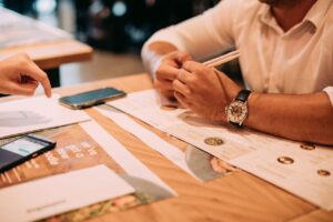 Two adults discussing a menu at a restaurant table with chopsticks and phones.